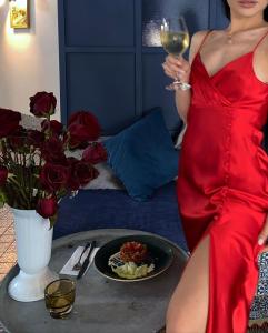 拉夫达Villa Livia Boutique Apartments的穿着红色衣服的女人,拿着一杯酒