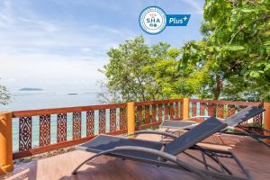 皮皮岛Phi Phi Natural Resort-SHA Extra Plus的一张椅子,坐在甲板上,俯瞰水面
