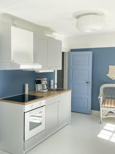 VejbystrandMagnarp Strandbad的厨房配有白色橱柜和蓝色的墙壁