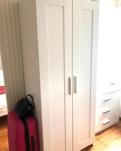 赫尔辛基Villa Alex的旁边装有粉红色手提箱的白色橱柜