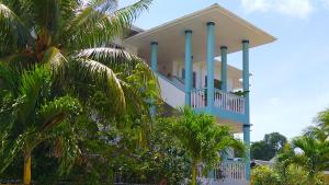 安塞罗亚莱泰蕾兹别墅酒店的白色的房屋,有蓝色的柱子和棕榈树