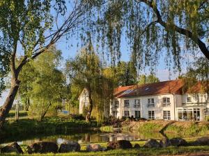 塞兰Van der Valk Golfhotel Serrahn - Adult Only的前面有池塘的大房子