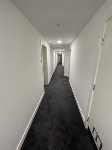达格纳姆London Dagenham Apartments的一条空的走廊,有白色的墙壁和黑色的地毯