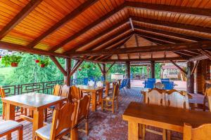 布克维Villa Elena SPA & Resort的一间设有木桌和椅子的餐厅以及屋顶