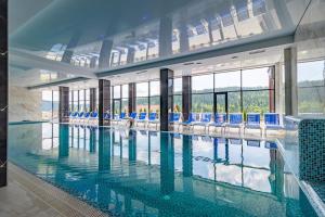 布克维Villa Elena SPA & Resort的大楼内带蓝色椅子的大型游泳池