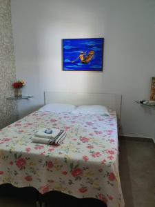 库亚巴Suite 03 - Independente, privativa e aconchegante的一间卧室配有一张带鲜花毯子和墙上绘画的床。