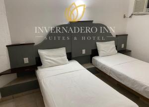 韦拉克鲁斯Invernadero Inn的墙上有标牌的房间的两张床