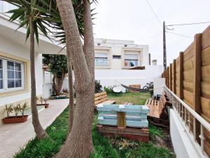 费雷尔Cloud to Chill Surfhouse Baleal的一座棕榈树的房子和庭院内的长凳