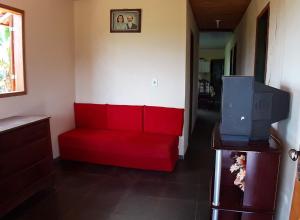 伊坦贝-杜马图登特鲁Casa grande, bem espaçosa, em Itambe do Mato Dentro, Cabeça de Boi的客厅设有一张红色沙发,配有电视