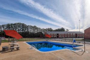 麦迪逊Red Roof Inn PLUS+ Huntsville – Madison的一个带野餐桌的游泳池和一座建筑