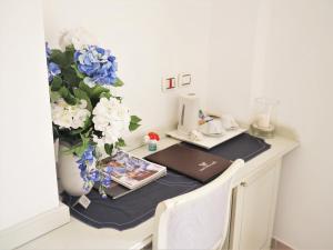 阿纳卡普里其赛雷别墅酒店的一张带笔记本电脑的桌子和一个花瓶,花朵是蓝色和白色