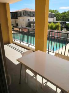 瑞维尼亚克Appartement T2 - Golf de Fontcaude - Résidence Coté Green à Juvignac 34990的阳台配有桌椅,享有泳池美景