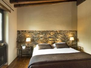 菲维扎诺艾托奇维奇度假屋的一间卧室设有一张大床和石墙