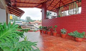 马迪凯里Treebo Trend Avyukta Stay的一座种植了盆栽植物和红砖墙的庭院