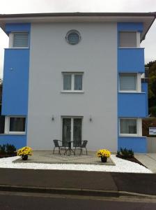 巴特基辛根Ferienwohnung Viktoria的蓝色和白色的建筑,前面有两把椅子
