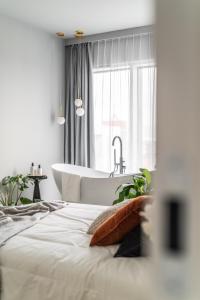波兹南Choya Apartments的白色的浴室设有浴缸和床。