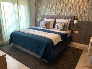巴拉顿菲赖德豪利克公寓酒店的一间卧室配有一张带蓝色毯子和枕头的床。