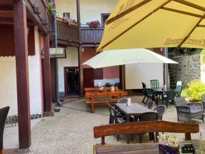 HronecCountry House & Restaurant Hronec的庭院配有桌椅和黄色雨伞。