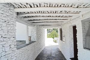 潘潘埃拉Casa Rural Vata 1 y 2 Pampaneira Alpujarra的石头建筑的走廊,带有木制天花板