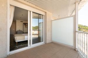 奥伦塞Hotel Condado Ourense的通往阳台的大型滑动玻璃门,阳台配有床