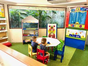累西腓Kastel Manibu Recife - Boa Viagem的两个孩子坐在游戏室的桌子上