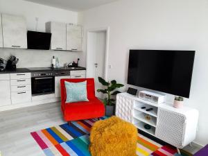 森夫滕贝格PB Ferienwohnungen - FeWo 6 - Stilvoll eingerichtetes Apartment im Herzen Senftenbergs的客厅配有红色椅子和平面电视