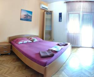 斯普利特伊洛斯酒店的一间卧室配有一张带紫色床单的大床