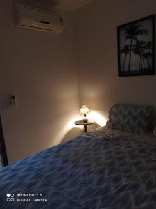 MaxaranguapePARAÍSO DE MARACAJAÚ - BEIRA MAR的一间卧室配有一张床和一张带台灯的桌子
