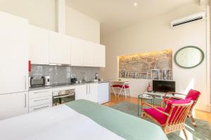 波尔图Inside Porto Apartments - Mouzinho的一间厨房,里面配有白色的橱柜和粉红色的椅子