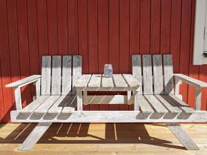 Hemse4 person holiday home in HEMSE的红色墙前的木凳和野餐桌
