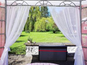 Hemse4 person holiday home in HEMSE的一个带白色窗帘的户外坛,享有庭院的景色