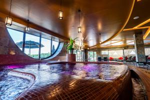 埃格尔Allure Healthy Hotel & Spa的一座紫色灯的建筑中央的游泳池