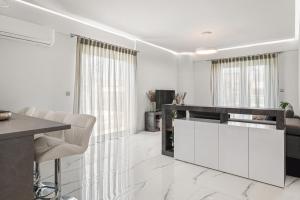 雅典BillyMare central Glyfada apartment的厨房配有白色橱柜和桌椅