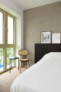 瓦勒海姆Parkhotel Waregem的一间卧室配有一张床、一把椅子和窗户。