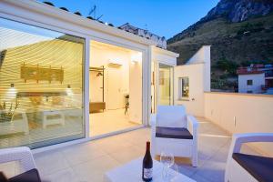 卡斯泰拉马莱Porta del Golfo Apartments & Suites的庭院配有白色的椅子和一张桌子及一瓶葡萄酒