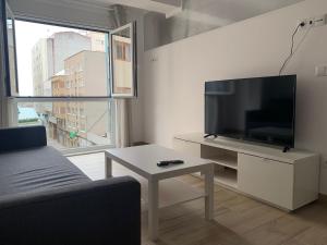 拉科鲁尼亚Oxford Suites Ciudad de la Coruña的客厅配有平面电视和桌子。