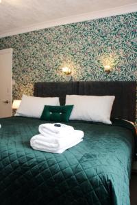 温德米尔Cambridge House room only accommodation for Adults的一张绿床,上面有一堆毛巾