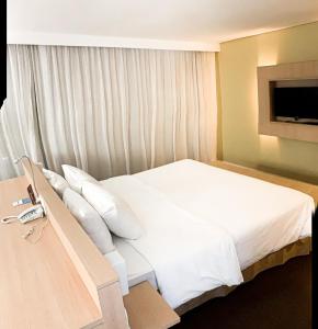 马瑙斯马瑙斯美居酒店的一间卧室配有带白色床单和枕头的床。