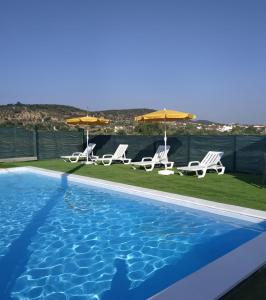 新蒙特莫尔Girassol Alojamento Local的一个带两把草坪椅和遮阳伞的游泳池
