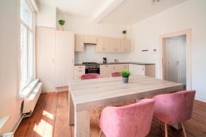 安特卫普Antwerp Old Town Centrum Apartment的厨房配有木桌和粉红色的椅子
