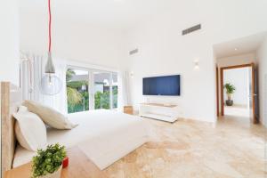 蓬塔卡纳Luxury 5-room modern villa with movie theater at exclusive Punta Cana golf and beach resort的一间白色卧室,配有一张大床和一台电视