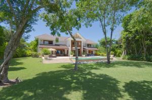 蓬塔卡纳Amazing 4-bedroom tropical villa with private pool and golf course view at luxury resort的前面有树木的院子的房子