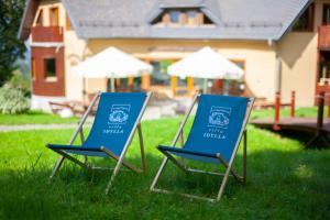 普热谢卡Villa Idylla的两把蓝色椅子坐在房子前面的草上
