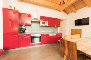 萨姆瑙恩Chasa Sulai Appartements的厨房配有红色橱柜和木桌