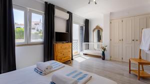 法鲁3 Bed Holiday Home Lakeside Village Quinta Do Lago的一间卧室设有一张床、一台电视和窗户。