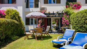 法鲁3 Bed Holiday Home Lakeside Village Quinta Do Lago的庭院配有桌椅和遮阳伞。