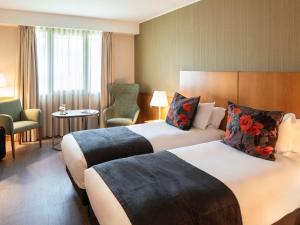 加亚新城波尔图盖亚美居酒店的酒店客房带两张床和一张桌子以及椅子。