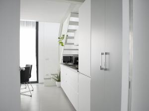 米兰Brand new apartments Ortiquattro的白色的厨房配有白色的橱柜和桌子