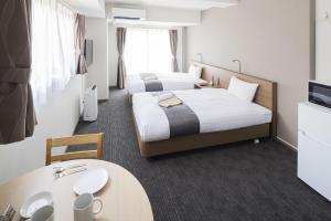 长崎Coruscant Hotel NagasakiekiⅢ的酒店客房设有两张床和一张桌子。