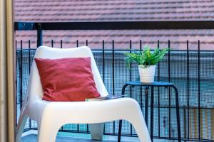 桑特伊阿Quick Home Agatha Apt的白色椅子坐在带红色枕头的阳台上